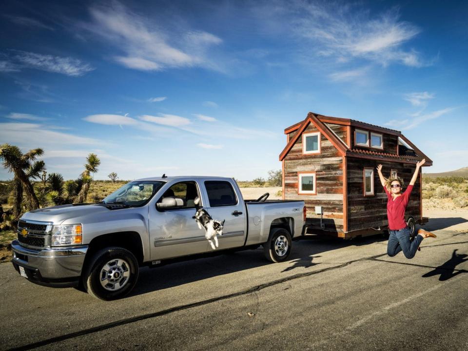 Jenna Kausal jumping in the air outside her tiny house