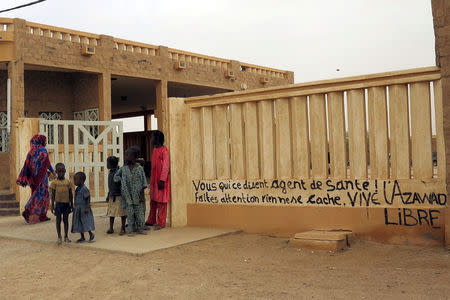 Children stand in front of a health clinic in Kidal, Mali, July 23, 2015. The graffiti reads, "You who say you're a health worker, be careful, nothing is hidden. Long live Azawad!" To match Analysis MALI-SECURITY/ REUTERS/Adama Diarra