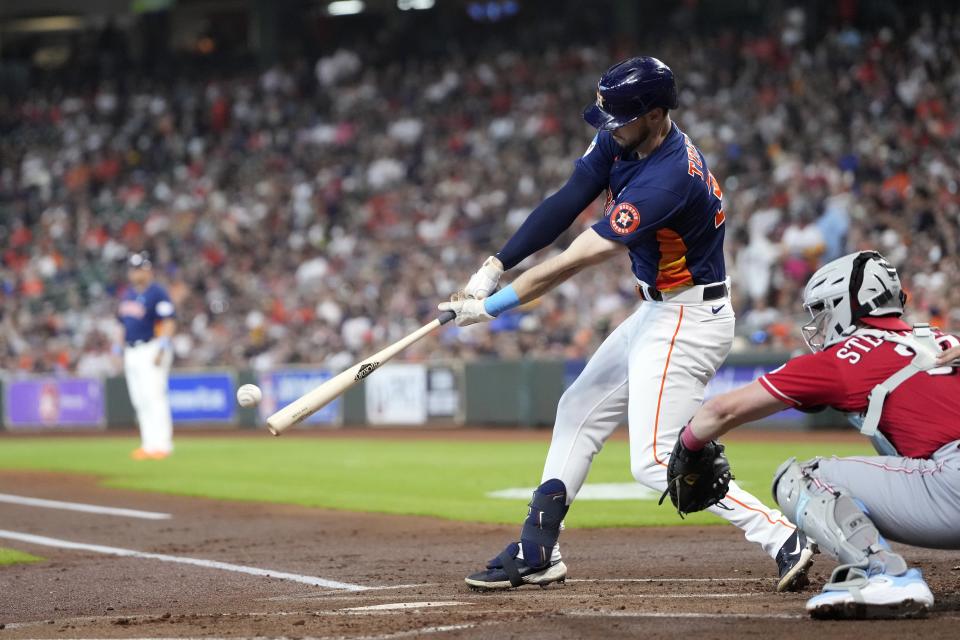 Houston Astros' Kyle Tucker, left, hits an RBI single as Cincinnati Reds catcher Tyler Stephenson reaches for the pitch during the first inning of a baseball game Sunday, June 18, 2023, in Houston. (AP Photo/David J. Phillip)