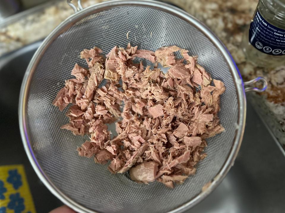 Shredded tuna in a strainer.