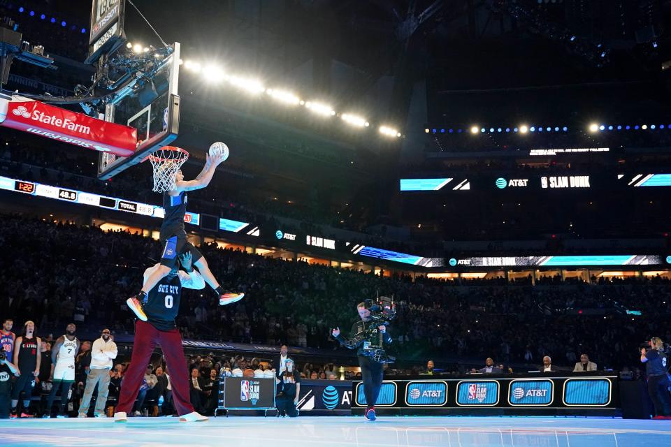 Mac McClung dunks the ball over Shaquille O'Neal during the slam dunk competition.