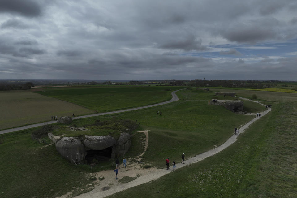 People walk by a bunker in Longues-sur-Mer, Normandy, Thursday, April 11, 2024. On D-Day, Charles Shay was a 19-year-old Native American army medic who was ready to give his life — and actually saved many. Now 99, he's spreading a message of peace with tireless dedication as he's about to take part in the 80th celebrations of the landings in Normandy that led to the liberation of France and Europe from Nazi Germany occupation. (AP Photo/Thibault Camus)