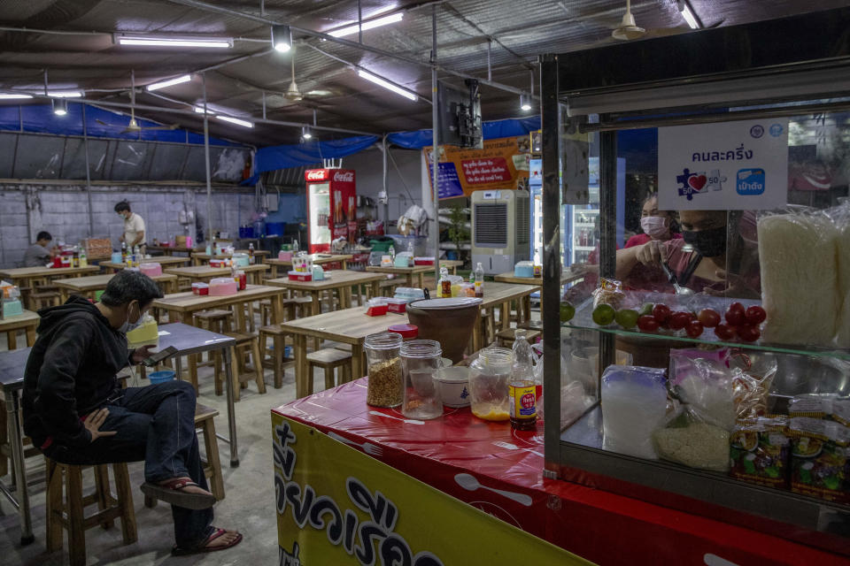 A man waits for his take away food at a restaurant in Bangkok, Thailand, Monday, Jan. 4, 2021. For much of 2020, Thailand had the coronavirus under control. After a strict nationwide lockdown in April and May, the number of new local infections dropped to zero, where they remained for the next six months. However, a new outbreak discovered in mid-December threatens to put Thailand back where it was in the toughest days of early 2020. (AP Photo/Gemunu Amarasinghe)