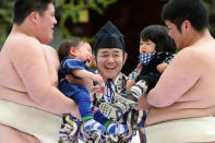 Student sumo wrestlers carry crying babies beside a referee (C) clad in a traditional costume during the "Baby-cry Sumo" competition at Sensoji temple in Tokyo on April 21, 2012. Some 100 babies aged under one took part in the annual baby crying contest. Japanese parents believe that sumo wrestlers can help make babies cry out a wish to grow up with good health. AFP PHOTO/Toru YAMANAKA