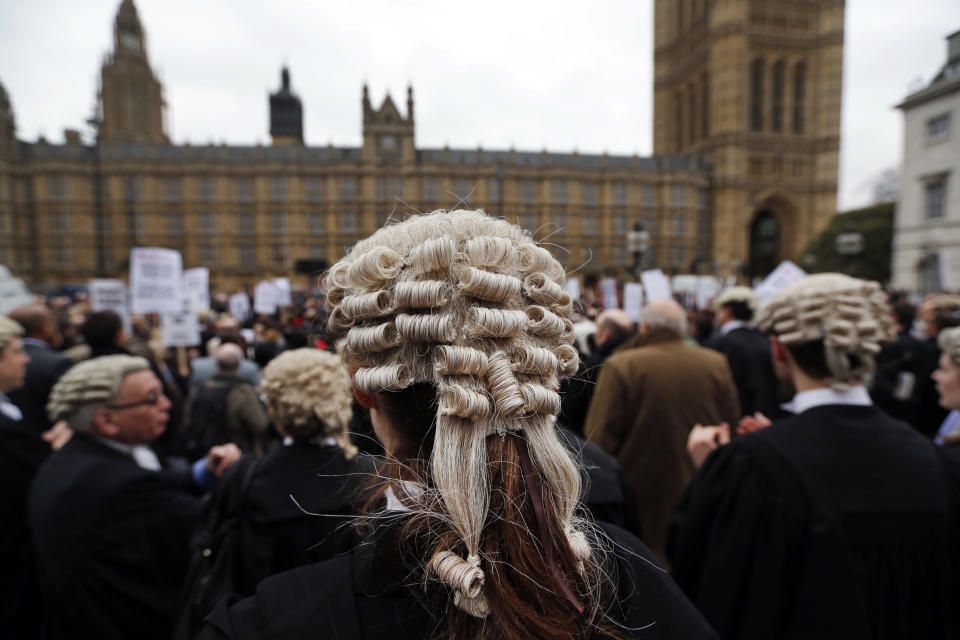 Lawyers in their full court dress of wigs and gowns, participate in a rally to protest against legal aid cuts, across from the Houses of Parliament in central London, Friday, March 7, 2014. The protest coincides with a nationwide demonstration of non-attendance of lawyers which will affect hundreds of cases across the country. (AP Photo/Lefteris Pitarakis)