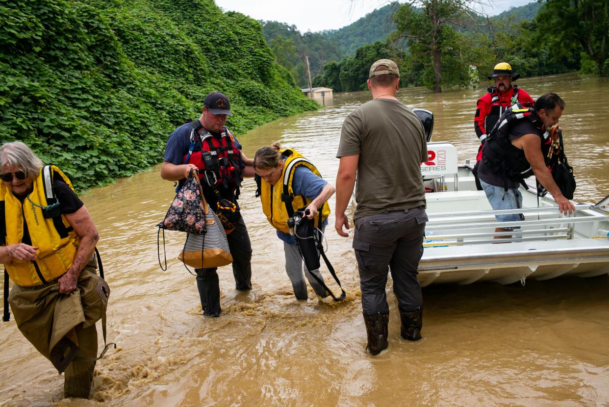 Members of a rescue team assist a family out of a boat on Thursday in Quicksand, Ky. 