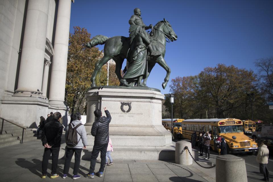 Visitors to the American Museum of Natural History in New York look at a statue of Theodore Roosevelt, flanked by a Native American man and African American man. The statue is headed to the Theodore Roosevelt Presidential Library in Medora, N.D.