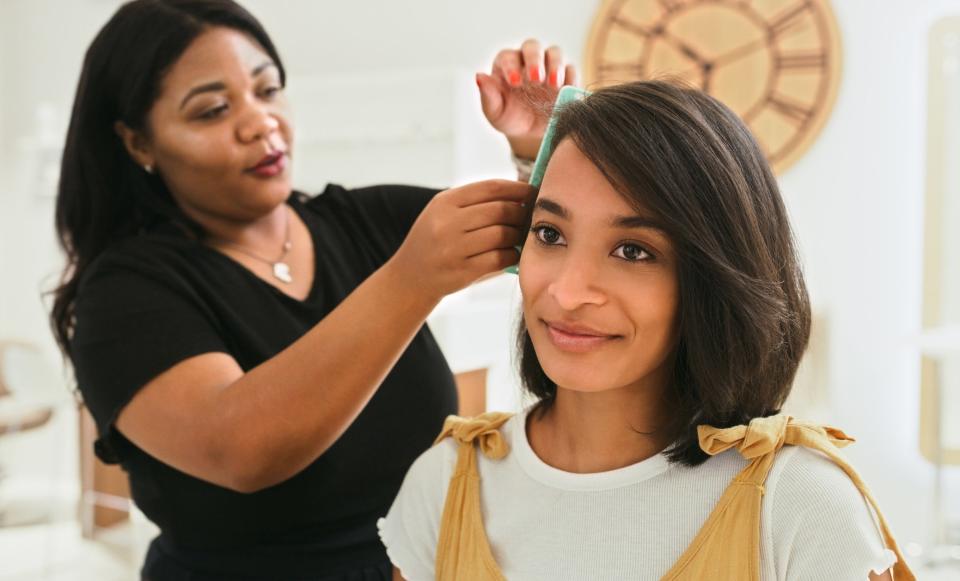 A woman doing another woman's hair
