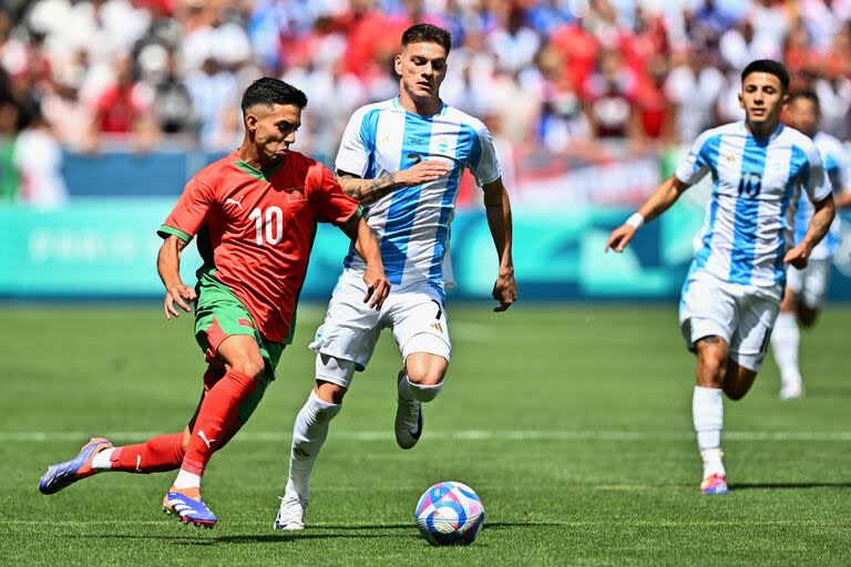 Ilias Akhomach quiere escapar a la presión de Kevin Zenon  y Thiago Almada. (Photo by Arnaud FINISTRE / AFP)