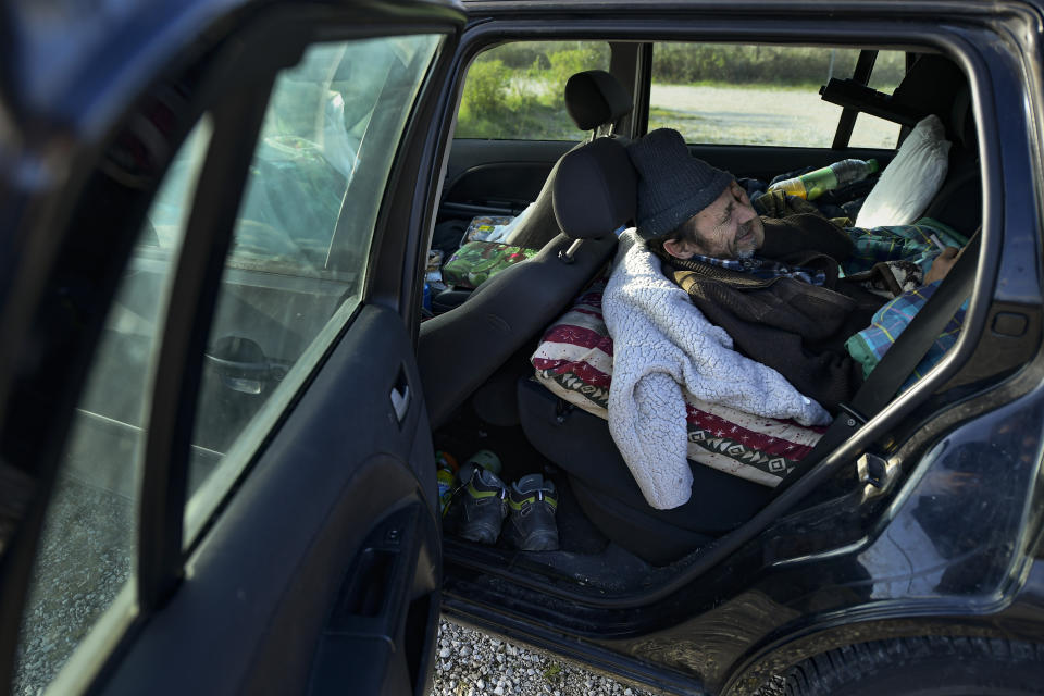 Juan Jimenez, 60, lies down in his car which is now his home, in Pamplona, northern Spain, Thursday, March 18, 2021. Jimenez has been forced to dwell in his second-hand Ford for close to a year after seeing his life collapse when he and his wife bought a bigger house, only for mortgage payments to spiral out of control and for their marriage to crumble after the economic slowdown caused by the coronavirus pandemic destroyed his financial stability. (AP Photo/Alvaro Barrientos)