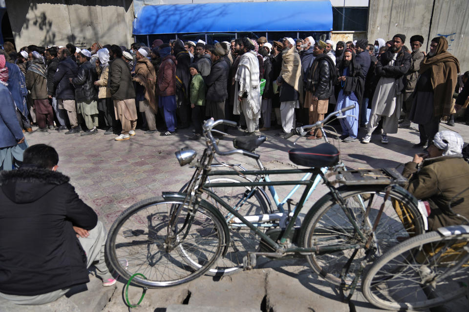 Afghans lineup to enter a bank, in Kabul, Afghanistan, Sunday, Feb. 13, 2022. During a press conference in Kabul on Sunday, former President Karzai called a White House order freeing $3.5 billion in Afghan assets for America's 9/11 families “an atrocity against the Afghan people." (AP Photo/Hussein Malla)