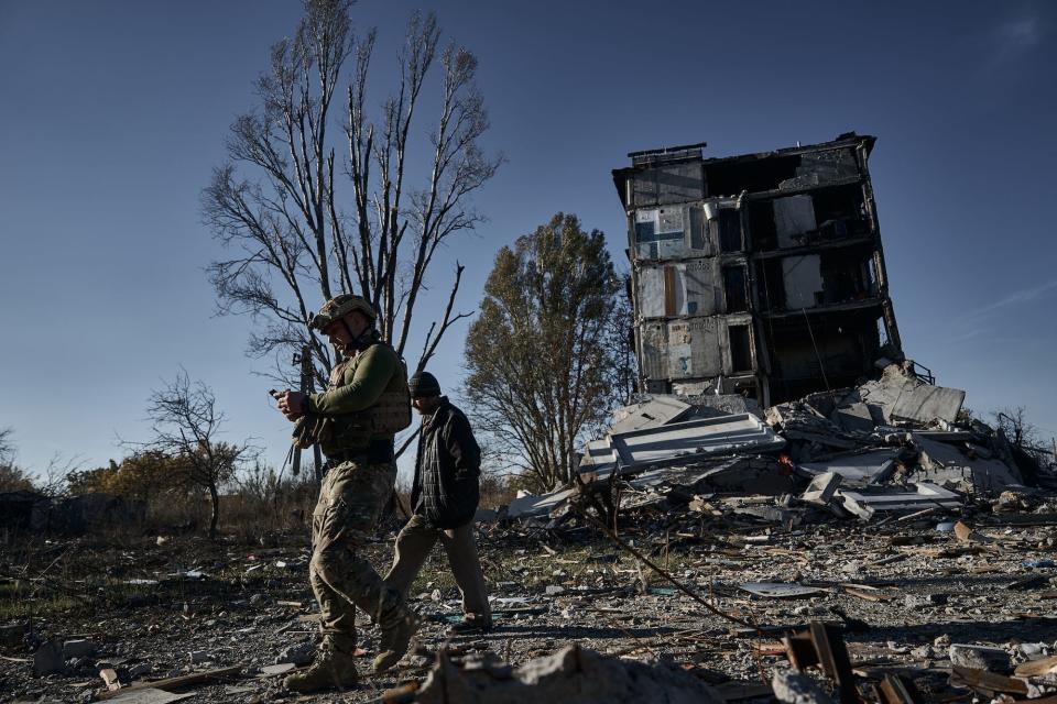 A Ukrainian soldier from the "White Angel" special unit, a local and a dilapidated house in the background