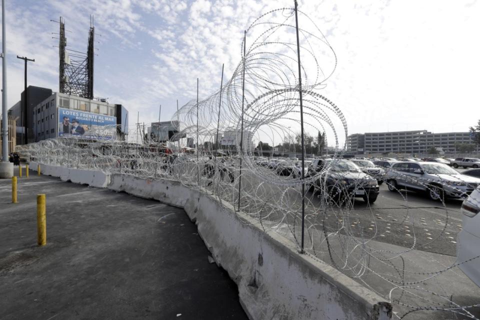 A través del muro rematado con concertina se ven los vehículos alineados para cruzar hacia Estados Unidos desde Tijuana, México, en el punto de acceso de San Ysidro. Los ladrones se han estado llevando el alambrado y vendiéndolo en Tijuana para reforzar la seguridad de los hogares. (Gregory Bull/ASSOCIATED PRESS)