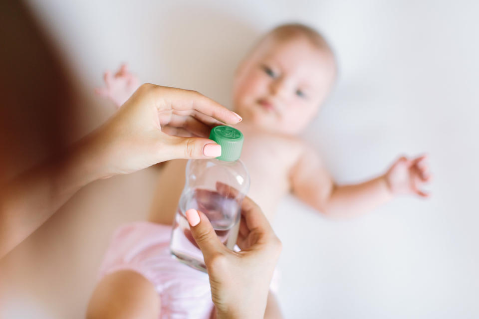 A mother putting baby oil on her baby