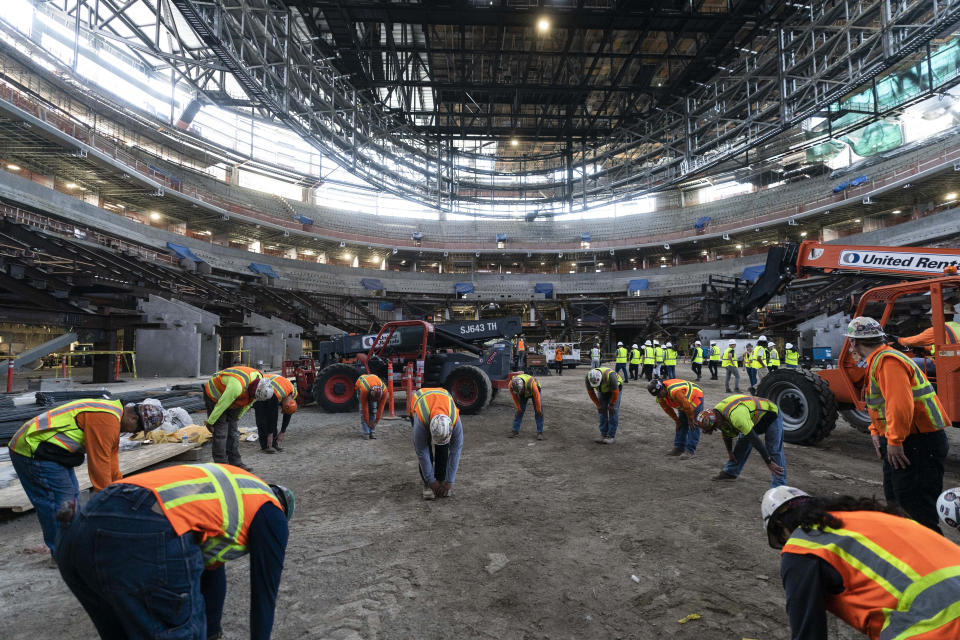 Construction workers stretch before working as members of the media tour the Los Angeles Clippers' Intuit Dome in Inglewood, Calif., Thursday, June 22, 2023. The arena is expected to be completed in time for the 2024-25 NBA season. (AP Photo/Jae C. Hong)