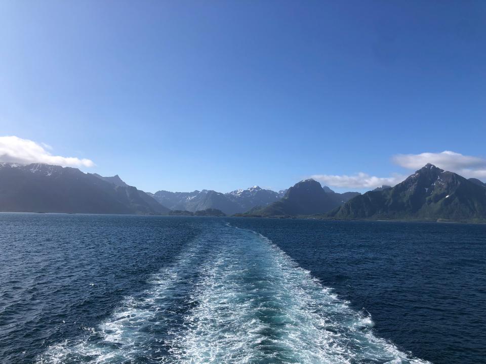 The view from a ferry: blue water rippling and mountains in the background.