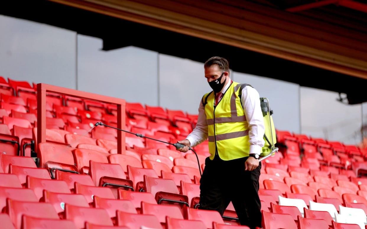 A steward disinfects the stands after the attending fans leave the grounds at the end of the Sky Bet League One match at The Valley, London - Steven Paston/PA