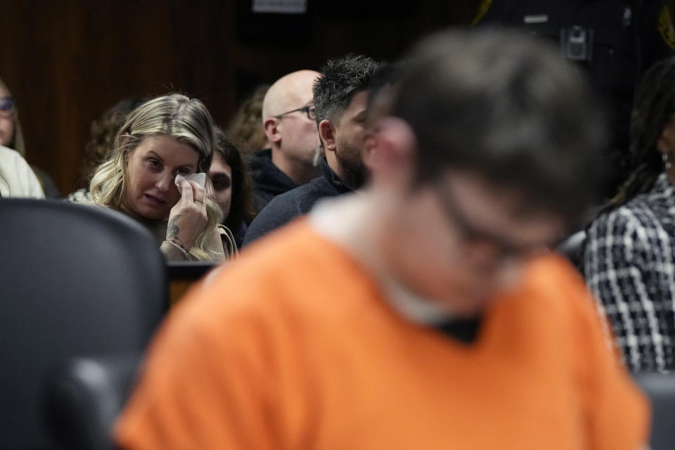 Ethan Crumbly, foreground, looks downward as victim family members listen to impact statements, Friday, Dec. 8, 2023, in Pontiac, Mich. Crumbly was sentenced to life in prison for killing four students, wounding more and terrorizing Michigan's Oxford High School in 2021. A judge Friday rejected pleas for a shorter sentence and ensured that Crumbley, 17, will not get an opportunity for parole. (AP Photo/Carlos Osorio)