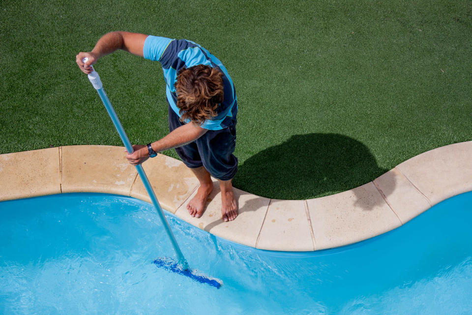 Pool guy celaning a pool with vacuum cleaner
