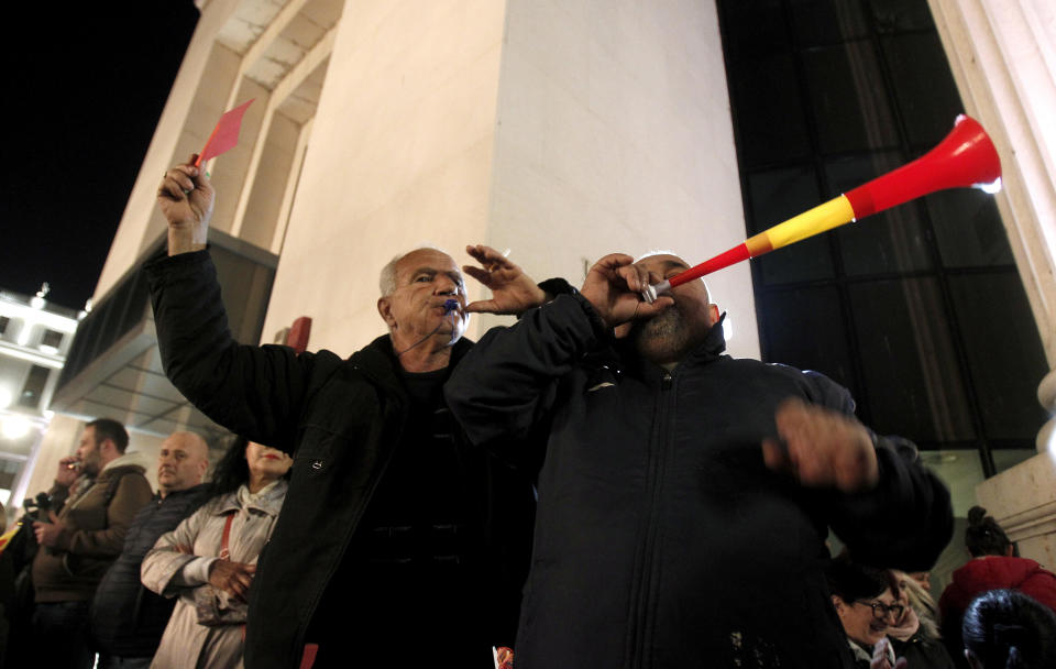 People chant slogans and play a vuvuzela during a protest march organized by the opposition conservative VMRO-DPMNE party, starting outside the Public Prosecutor's office and ending in front of the complex of national courts, in Skopje, North Macedonia, Tuesday, Feb. 25, 2020. Thousands of conservative opposition party supporters were marching in North Macedonia's capital Skopje late on Tuesday, accusing the outgoing leftist government for strongly influencing prosecution and court decisions. (AP Photo/Boris Grdanoski)