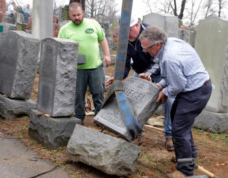 Spencer Pensoneau, Ron Klump and Philip Weiss (L-R), of Weiss and Rosenbloom Monument company, work to right toppled Jewish headstones after a weekend vandalism attack on Chesed Shel Emeth Cemetery in University City, a suburb of St Louis, Missouri, U.S. February 21, 2017. REUTERS/Tom Gannam