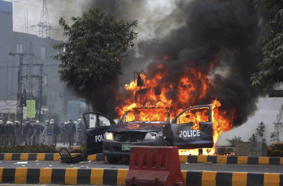 Police officers gather next to a burning police vehicles that were set on fire by angry lawyers during clashes in Lahore, Pakistan, Wednesday, Dec. 11, 2019. Hundreds of Pakistani lawyers, angered over alleged misbehavior of some doctors toward one of their colleagues last month, stormed a cardiology hospital in the eastern city of Lahore, setting off scuffles with the facility's staff and guards that left heart patients unattended for several hours. (AP Photo/K.M. Chaudary)