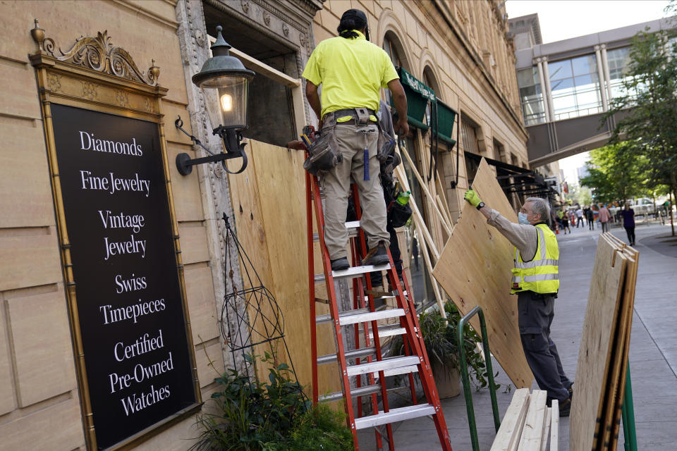 Workers board up windows along the famous Nicollet Mall Thursday, Aug. 26, 2020, in downtown Minneapolis. An emergency curfew expired and downtown Minneapolis was calm Thursday morning after a night of unrest that broke out following what authorities said was misinformation about the suicide of a Black homicide suspect. (AP Photo/Jim Mone)