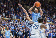 North Carolina forward Puff Johnson (14) looks to shoot while guarded by Duke guard Jacob Grandison (13) and forward Mark Mitchell (25) in the first half of an NCAA college basketball game on Saturday, Feb. 4, 2023, in Durham, N.C. (AP Photo/Jacob Kupferman)