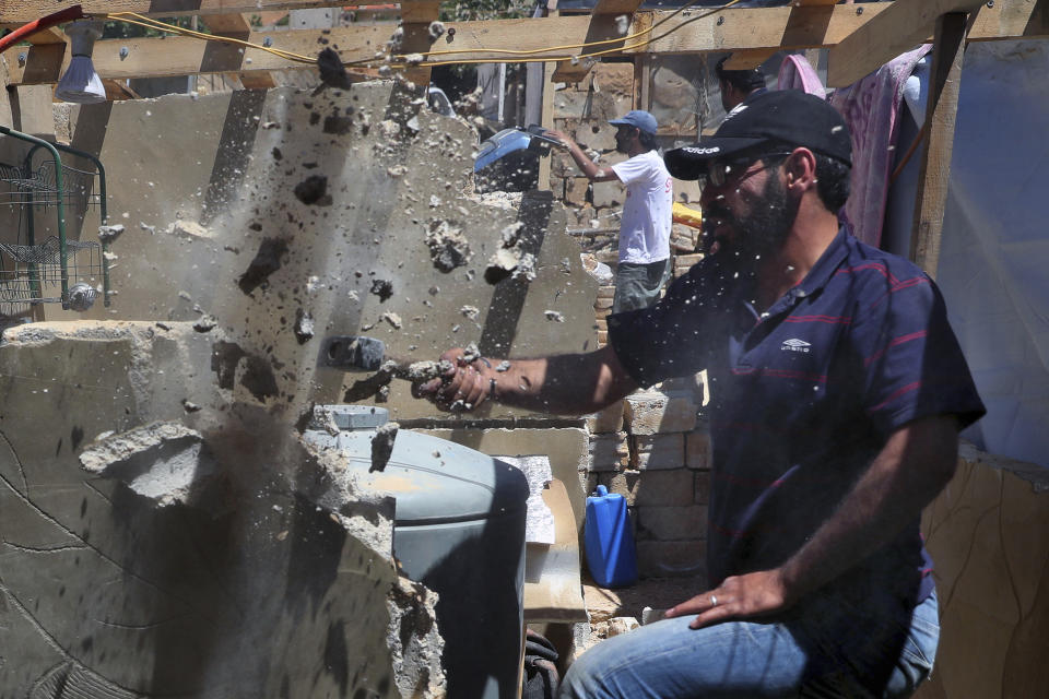 In this Sunday, June 16, 2019 photo, a Syrian refugee demolishes a concrete wall built inside his tent at a refugee camp in the eastern Lebanese border town of Arsal, Lebanon. Authorities in Lebanon are waging their most aggressive campaign yet against Syrian refugees, making heated calls for them to go back to their country and taking action to ensure they can’t put down roots. They are shutting down shops where Syrians work without permits and ordering the demolition of anything in their squalid camps that could be a permanent home. (AP Photo/Bilal Hussein)