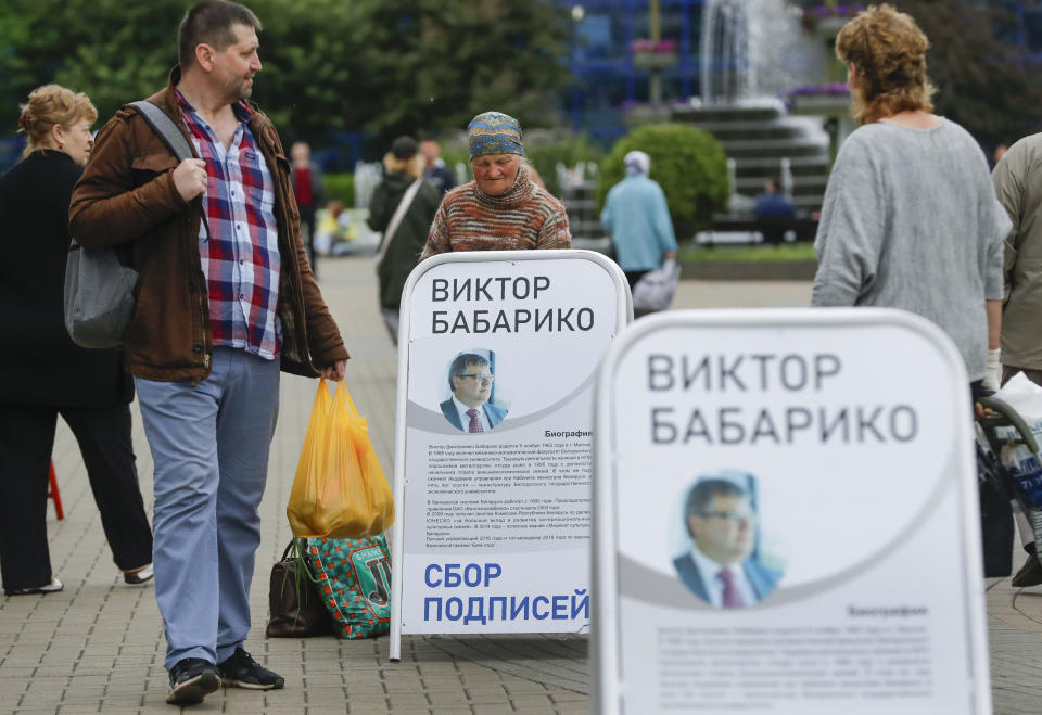 People pass informational posters for Viktar Babaryka, potential candidate in the upcoming presidential elections, in Minsk, Belarus, Sunday, June 14, 2020. The presidential campaign is underway in Belarus despite the coronavirus outbreak after the parliament and government refused to postpone the election scheduled for August 9. (AP Photo/Sergei Grits)