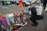 A woman lights a candle at a sidewalk memorial near the burned warehouse following the fatal fire in the Fruitvale district of Oakland, California, U.S. December 5, 2016. REUTERS/Lucy Nicholson