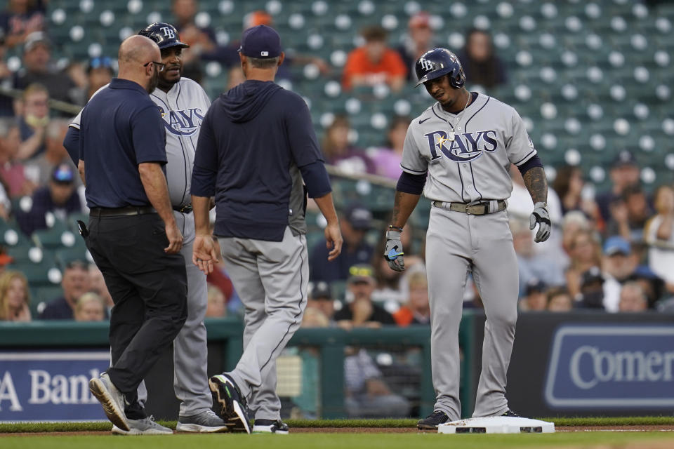 Tampa Bay Rays' Wander Franco, from right, grimaces on third base as manager Kevin Cash and a team trainer Joe Benge check on him with third base coach Rodney Linares (27)and against the Detroit Tigers in the first inning of a baseball game in Detroit, Friday, Sept. 10, 2021. Franco left the game. (AP Photo/Paul Sancya)