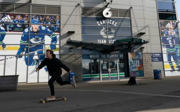 A skateboarder rides past a quiet Rogers Arena in downtown Vancouver last Thursday. (Jonathan Hayward/The Canadian Press - image credit)