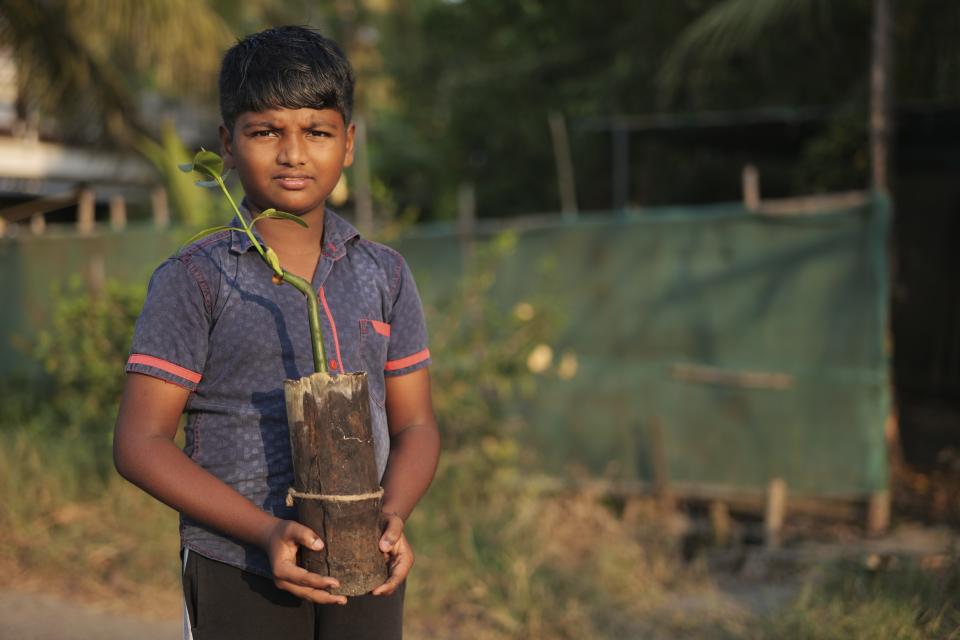 T. M. Akanitth, grandson of T. P. Murukesan, holds a mangrove sapling grown at their home nursery on Vypin Island, in Kochi, Kerala state, India, on March 4, 2023. Murukesan said he has planted over 100,000 mangroves in the area. (AP Photo/Shawn Sebastian)