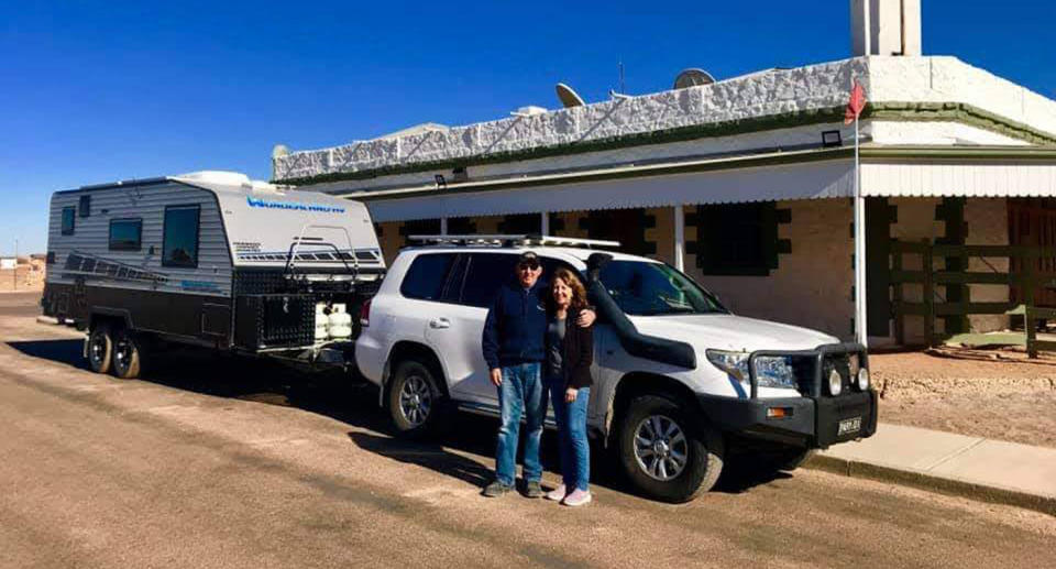 Steve and Leoni Pari standing in front of caravan while travelling through the Australian outback. 