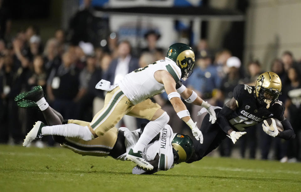 Colorado cornerback Travis Hunter (12) is dragged down after a short gain by Colorado State defensive back Henry Blackburn, back left, and defensive back Ayden Hector during the first half of an NCAA college football game Saturday, Sept. 16, 2023, in Boulder, Colo. (AP Photo/David Zalubowski)