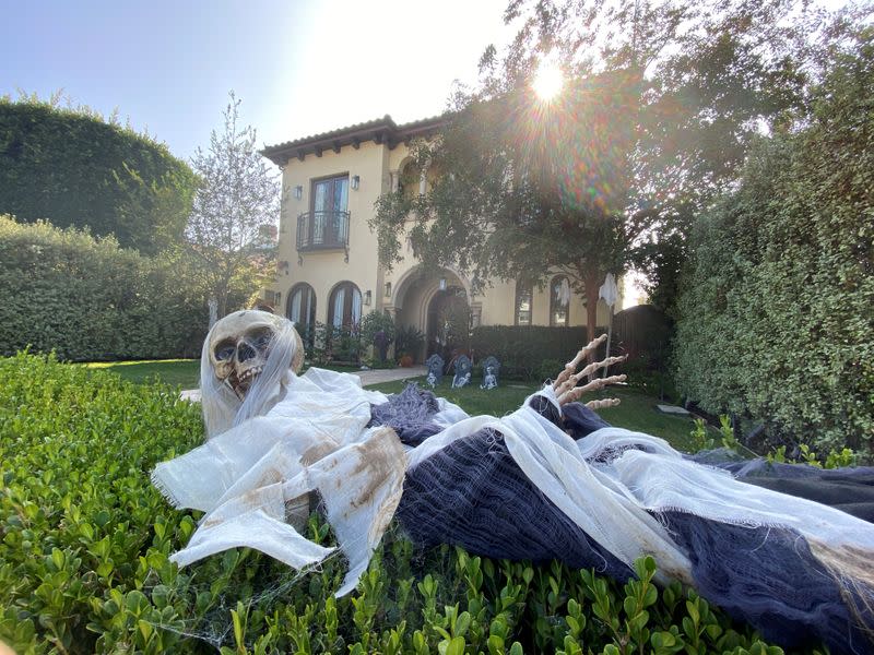 FILE PHOTO: A Halloween skeleton lies on the hedge outside a home in Los Angeles