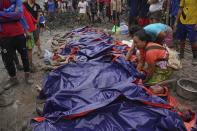 Women look at bodies shrouded in blue and red plastic sheets placed in a row on the ground Thursday, July 2, 2020 in Hpakant, Kachin State, Myanmar. At least 162 people were killed Thursday in a landslide at a jade mine in northern Myanmar, the worst in a series of deadly accidents at such sites in recent years that critics blame on the government's failure to take action against unsafe conditions. (AP Photo / Zaw Moe Htet)