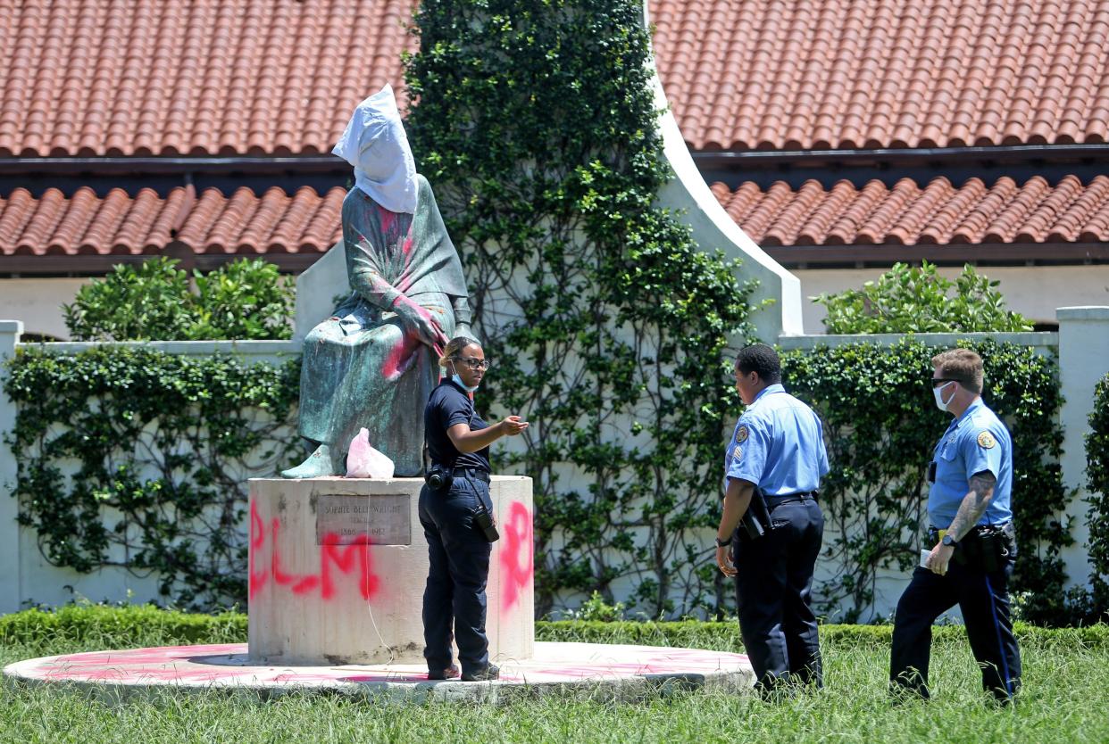 A crime scene technician with the New Orleans Police Department takes photos after the statue of educator Sophie Bell Wright, whose father served in the Confederate Navy and Army, was covered with a white hood and spray-painted with BLM on July 10, 2020, in New Orleans, Louisiana. The statue, one of several vandalized this week, was one of many located throughout New Orleans that protestors say celebrate white supremacy.