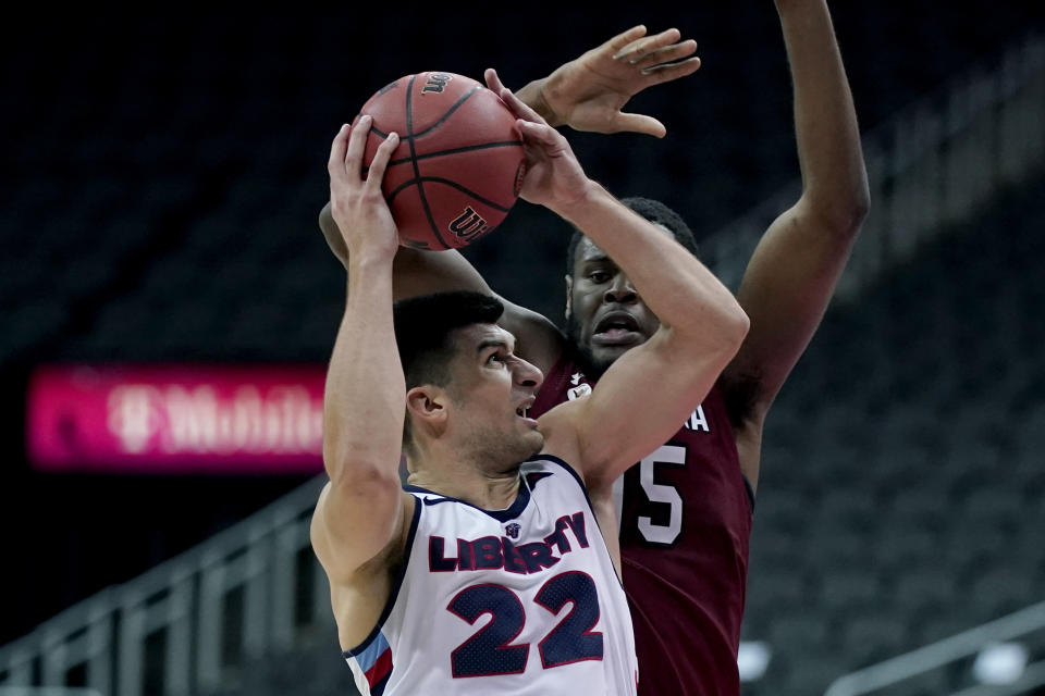 Liberty's Kyle Rode (22) shoots under pressure from South Carolina's Wildens Leveque, back, during the second half of an NCAA college basketball game Saturday, Nov. 28, 2020, at the T-Mobile Center in Kansas City, Mo. (AP Photo/Charlie Riedel)