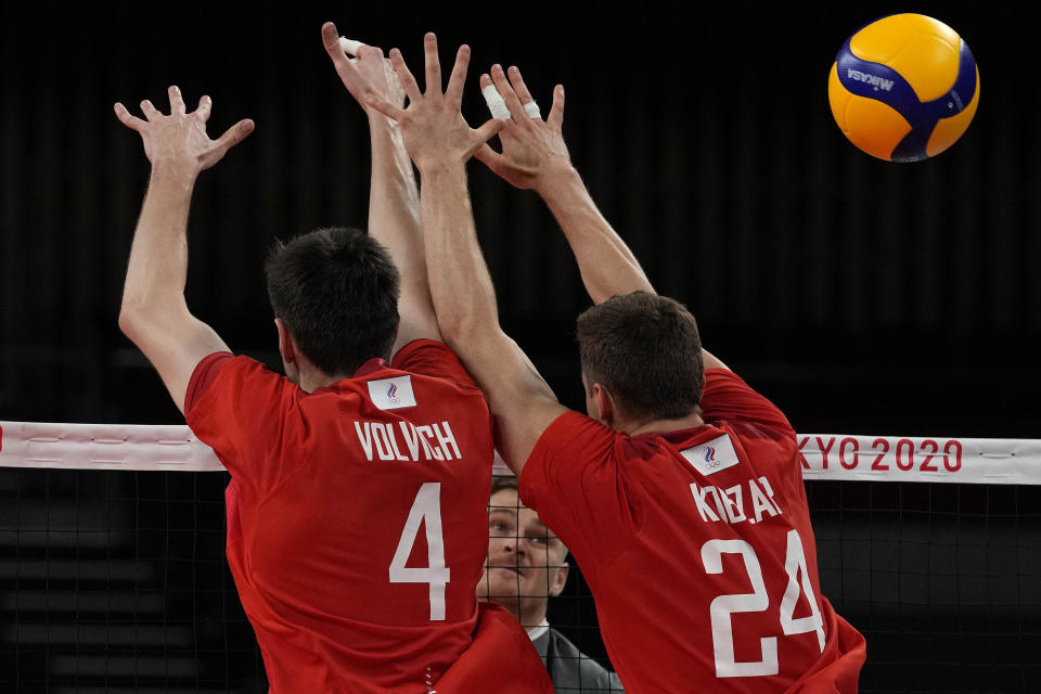 Canada's John Gordon Perrin, rear, spikes the ball past Artem Volvich, of the Russian Olympic Committee,, left, and Igor Kobzar, of the Russian Olympic Committee, during the men's volleyball quarterfinal match between Canada and Russian Olympic Committee at the 2020 Summer Olympics, Tuesday, Aug. 3, 2021, in Tokyo, Japan. (AP Photo/Frank Augstein)