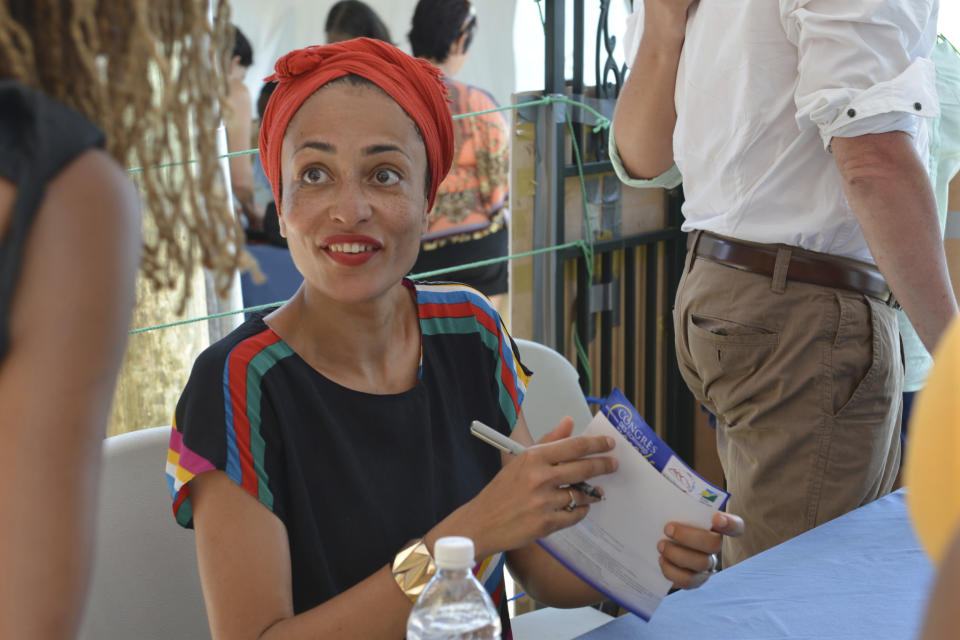 FILE - In a May 31, 2014, file photo, acclaimed novelist Zadie Smith signs a book for a fan in Treasure Beach, Jamaica. Ann Patchett, Michael Chabon and Smith were among the nominees announced Tuesday, Jan. 17, 2017, for the National Book Critics Circle Awards. (AP Photo/David McFadden, File)