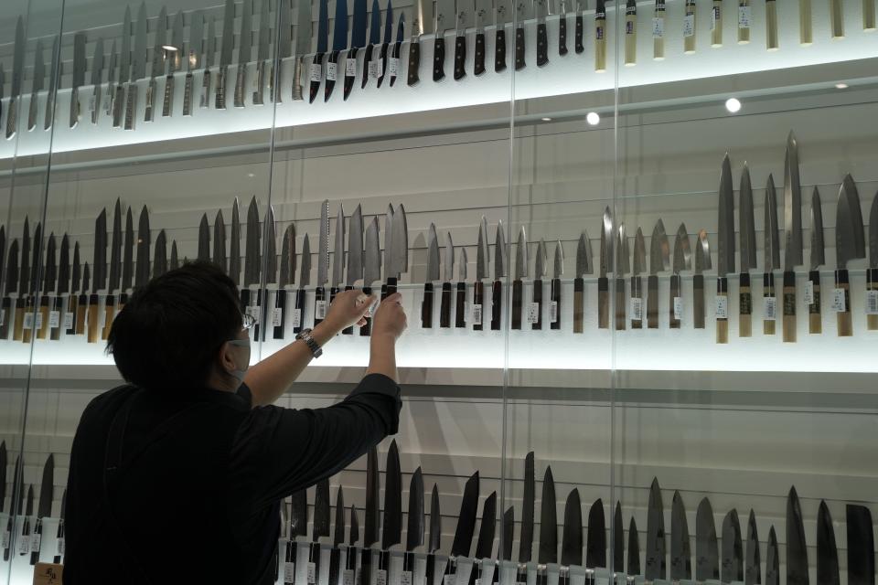 A staff arranges variety of kitchen knives at a kitchen knife store at "Toyosu Senkyaku Banrai," an Edo Period-themed hot spring complex on media preview eventat Toyosu Market Monday, Jan. 29, 2024, in Tokyo. Japan's biggest fish market on Thursday opened a long-awaited outer section with Japanese-style seafood restaurants and a spa for relaxation, as the wholesale venue that has struggled since relocating from the beloved Tsukiji market seeks to lure more visitors. (AP Photo/Eugene Hoshiko)