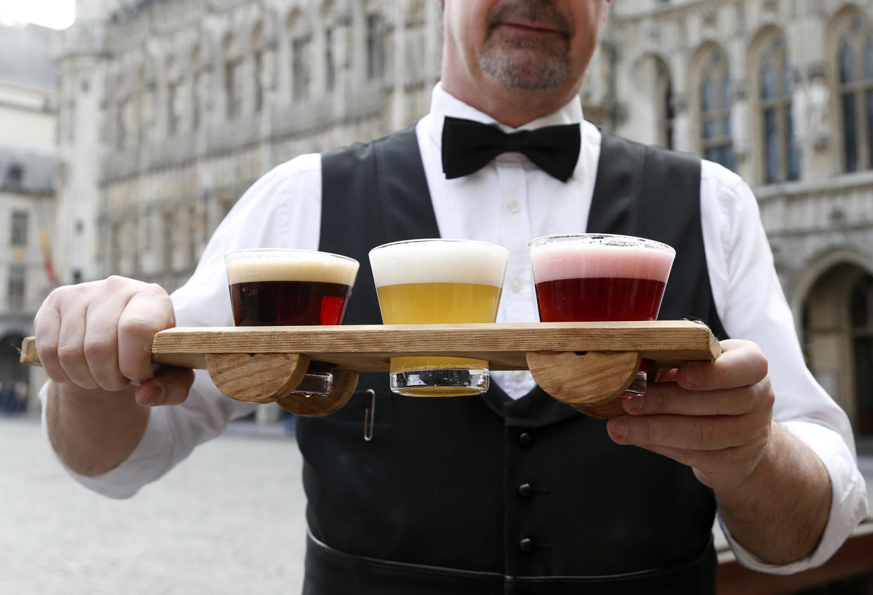 A waiter displays glasses of beer in the colours of the Belgian national flag on Brussels Grand Place, Belgium, March 9, 2016.  REUTERS/Francois Lenoir 