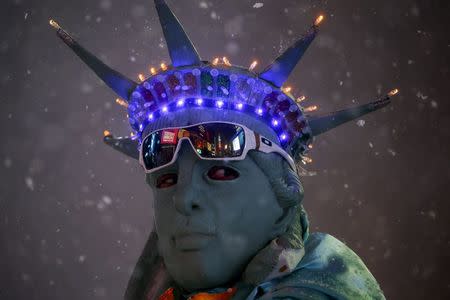 A man is seen posing as the Statue of Liberty during a snow storm in Times Square in the Manhattan borough of New York, January 23, 2016. REUTERS/Carlo Allegri