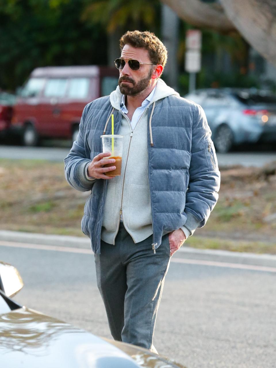 Ben Affleck in grey jacket holding iced coffee