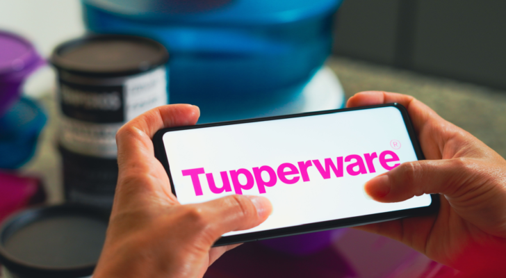 In this photo illustration, the Tupperware (TUP) logo is displayed on a smartphone screen and in the background various plastic products (canisters).