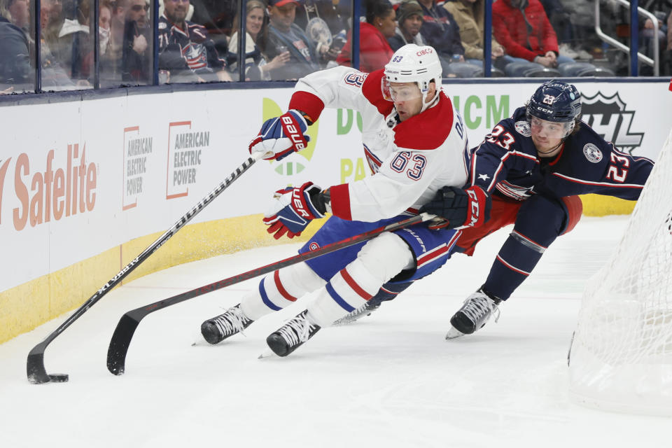 Montreal Canadiens' Evgenii Dadonov, left, carries the puck behind the net as Columbus Blue Jackets' Jake Christiansen defends during the first period of an NHL hockey game Thursday, Nov. 17, 2022, in Columbus, Ohio. (AP Photo/Jay LaPrete)