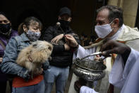 Manoli, left, wearing a face mask to prevent the spread of the coronavirus, holds her rabbit while Priest Cesar Magana blesses her pet during the feast of St. Anthony, Spain's patron saint of animals, in Pamplona, northern Spain, Sunday, Jan. 17, 2021. The feast is celebrated each year in many parts of Spain and people bring their pets to churches to be blessed. (AP Photo/Alvaro Barrientos)