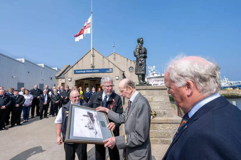The Duke of Kent receives a framed picture at the memorial site
